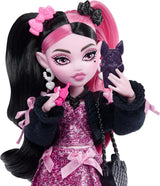 Panenka Monster High Draculaura v růžových šatech s mašlemi a černým svetrem s Count Fabulous Bat a 7 doplňky včetně ramen, rtěnky a tašky, JHK29